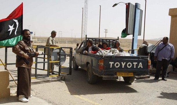 Rebel fighters stand guard while Libyan refugees cross the border at the southern Libyan and Tunisian border crossing of Dehiba