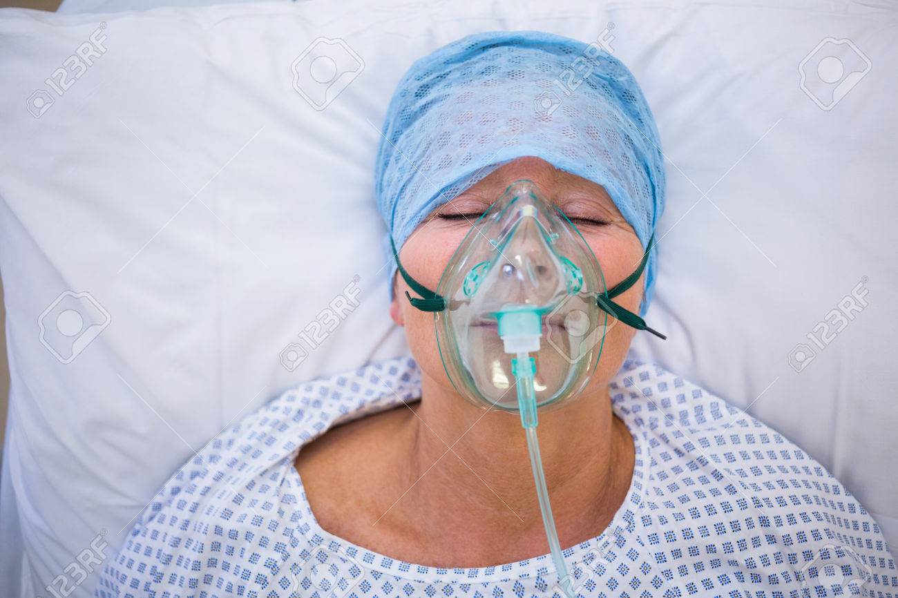 Patient wearing oxygen mask lying on bed in hospital